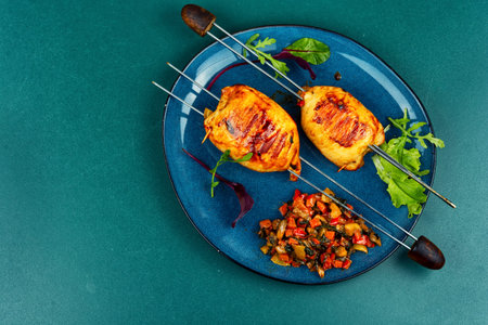 Grilled chicken skewers served with sauteed vegetables and fresh greens. Copy space.