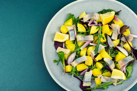 Seafood salad made with salted herring, boiled potatoes, red onion and mixed leafy greens. Space for text.