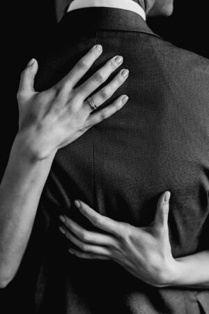 bride hugs the groom in a jacket with two hands in black and whiteの写真素材
