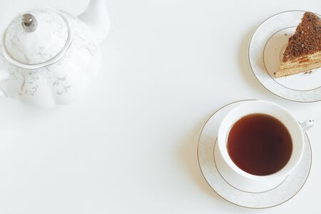 Strong tea in a white mug closeup on a background of yellow flowers against a white background and a teapotの写真素材