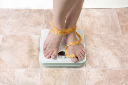 image of woman standing on a weight scaleの写真素材