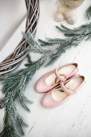 Children's shoes on a wooden table with a pine tree christmas decorationの写真素材