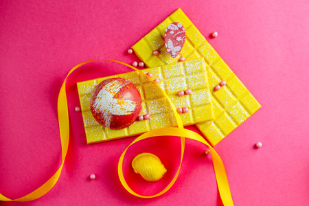 Sweet tasty milk yellow chocolate on pink background with ribbon