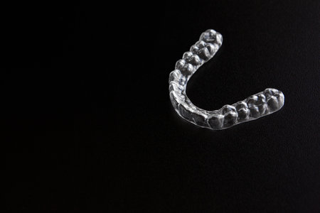 Transparent invisible orthodontic brackets, tooth aligners, plastic braces, mouth guard, retainers on a black backgroundの写真素材