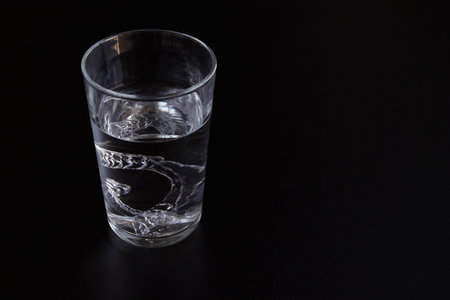 Transparent invisible orthodontic tooth aligners, retainers cleaning in a glass with water on a black backgroundの写真素材