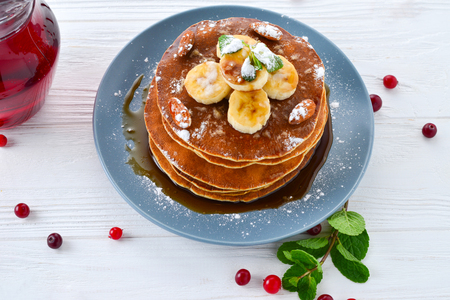Pancakes with caramel, banana and nuts decorated with cranberries and mint with juice.の写真素材