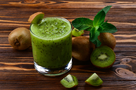 Healthy fresh kiwi smoothie in glass on a wooden background の写真素材