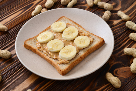 Peanut butter toast with banana slices  on wooden backgroundの写真素材