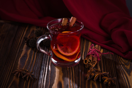 Still life, red mulled wine with oranges, anise and cinnamon sticks on a red background. Space for text or design.の写真素材