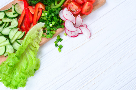Fresh sliced vegetables on a salad: radish, cherry, greens, cucumber, red pepper. Space for text or designの写真素材