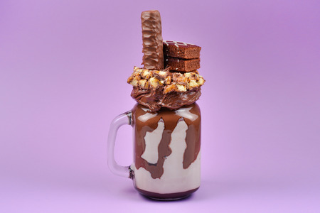 Chocolate extreme milkshake with brownie cake, chocolate paste and sweets. Crazy freakshake food trend. Copy spaceの写真素材