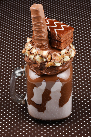 Chocolate extreme milkshake with brownie cake, chocolate paste and sweets. Crazy freakshake food trend. Copy spaceの写真素材