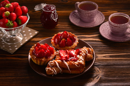 Tea drinking with tartlets and cakes with strawberriesの写真素材