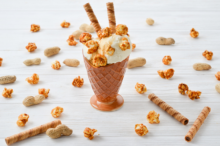 Ice cream with caramel and popcorn on a white table.の写真素材