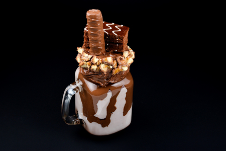 Chocolate extreme milkshake with brownie cake, chocolate paste and sweets. Crazy freakshake food trend. の写真素材