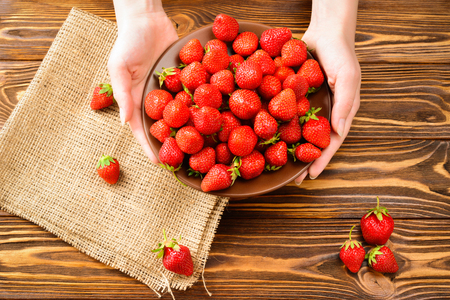 Woman holding a plate of strawberries. Healthy breakfast, Clean eating, vegan food concept. Top view. の写真素材