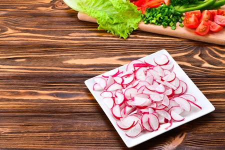 Fresh sliced vegetables on a salad: radish, cherry, greens, cucumber, red pepper. Space for text or designの写真素材