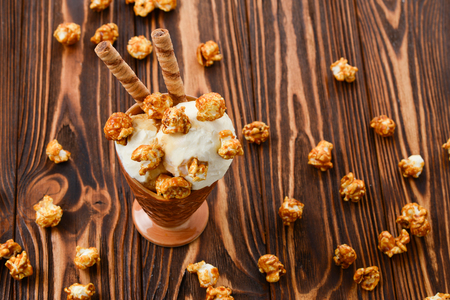 Ice cream with caramel and popcorn on a  black background. Space for text or design.の写真素材