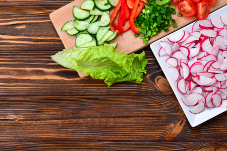 Fresh sliced vegetables on a salad: radish, cherry, greens, cucumber, red pepper. Space for text or designの写真素材