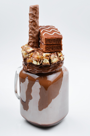 Chocolate extreme milkshake with brownie cake, chocolate paste and sweets. Crazy freakshake food trend. の写真素材
