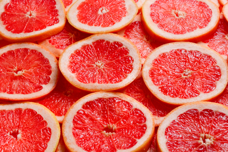 Grapefruit red juicy slices background. top viewの写真素材