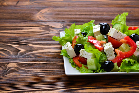 Greek salad on a wooden background. Space for text or design.の写真素材