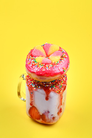 Freakshake. Extreme milkshake with strawberry, jelly sweets, donut.の写真素材