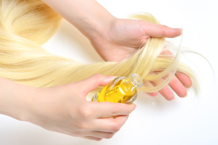 Oil hair treatment for woman with blond hair on white background. Spa, beauty salon. Hair care in modern spa salon.の写真素材