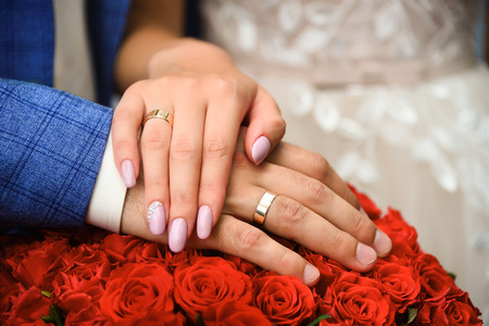 Hands and rings on wedding bouquet of roses close up.の写真素材
