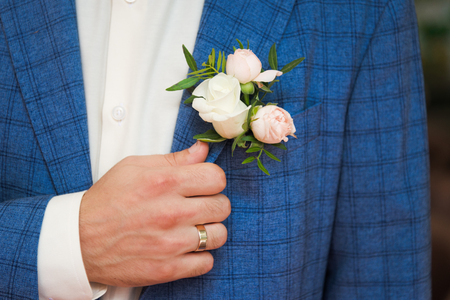 Groom in blue checkered suit with a  white and pale pink rose boutonniere, close up.の写真素材