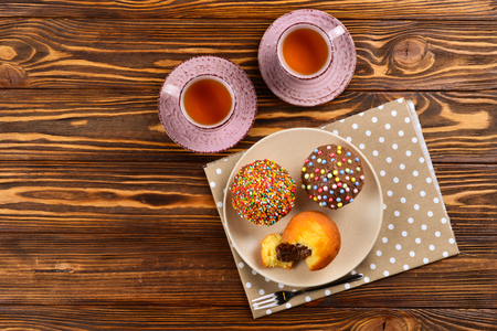 Baking with tea and chocolate on the table.  Two cups of tea with cupcakes and chocolate with a multicolored powder on the table.の写真素材