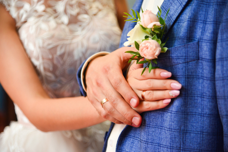 Hands and rings on wedding  pale pink rose boutonniere, close up.の写真素材