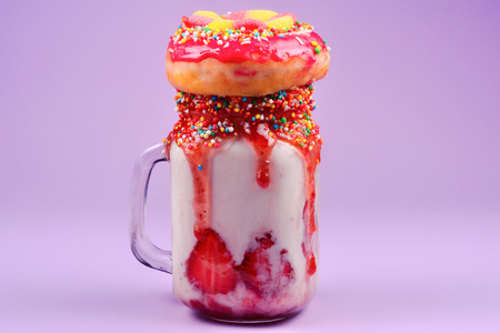 Freakshake. Extreme milkshake with strawberry, jelly sweets, donut.の写真素材