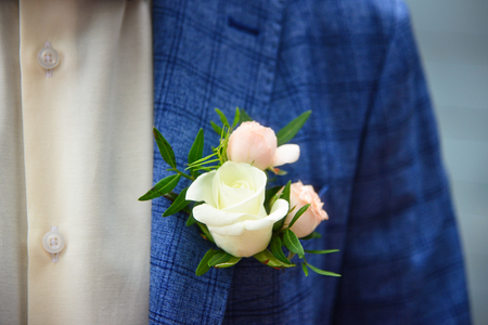 Groom in blue checkered suit with a white and pale pink rose boutonniere, close upの写真素材