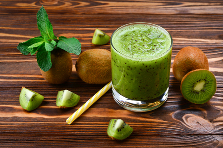 Healthy fresh kiwi smoothie in glass on a wooden backgroundの写真素材