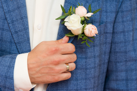 Groom in blue checkered suit with a  white and pale pink rose boutonniere, close up.の写真素材