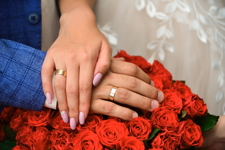 Hands and rings on wedding bouquet of roses close up.の写真素材