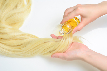 Oil hair treatment for woman with blond hair on white background. Spa, beauty salon. Hair care in modern spa salon.の写真素材
