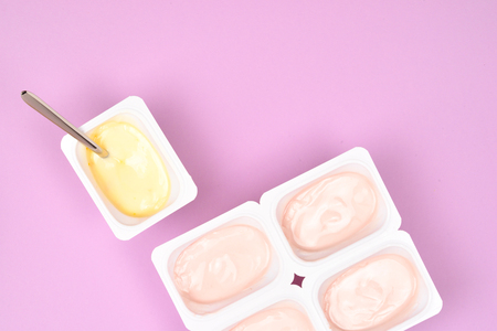 Plastic cup with tasty yogurt on lilac background. Top view. Space for text or design.の写真素材