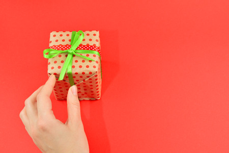 Present in woman hand on red background.