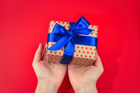 Present in woman hand on red background.の写真素材