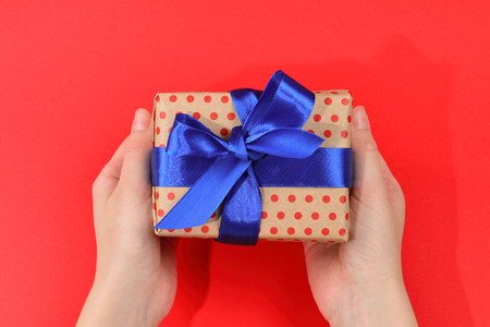 Present in woman hand on red background.の写真素材