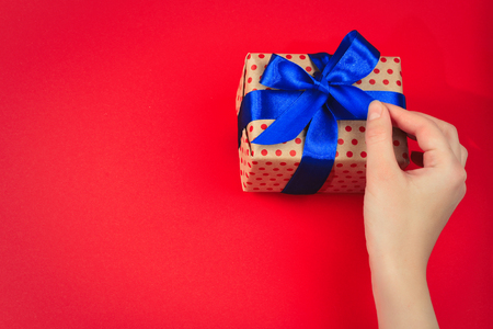 Present in woman hand on red background.の写真素材