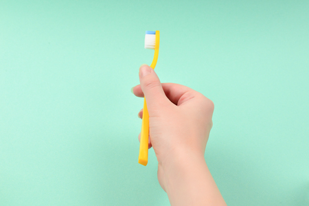 The woman holds toothbrushes in her hand on a green background.の写真素材