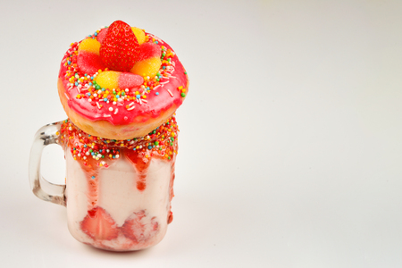 Freakshake. Extreme milkshake with strawberry, jelly sweets, donut.の写真素材