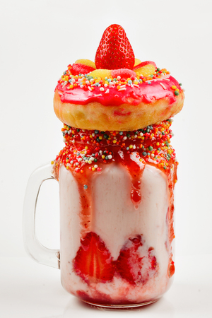 Freakshake. Extreme milkshake with strawberry, jelly sweets, donut.の写真素材