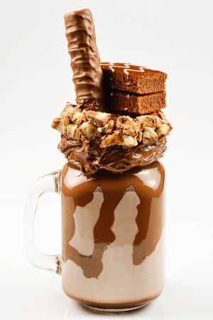 Chocolate extreme milkshake with brownie cake, chocolate paste and sweets. Crazy freakshake food trend. Copy spaceの写真素材