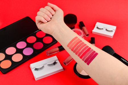 Lipstick swatches on woman hand. Professional makeup products with cosmetic beauty products, foundation, lipstick,  eye shadows, eye lashes, brushes and tools.の写真素材