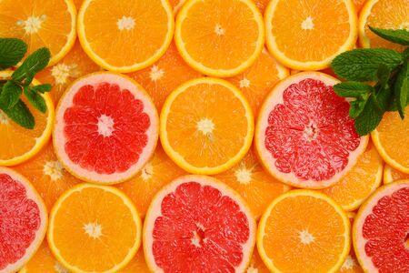 Slices of oranges and a grapefruits and mint as a background.の写真素材