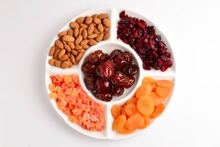 Mix of dried fruits and nuts. Apricot, raisin, cranberry, dates fruit. Isolated on a white...